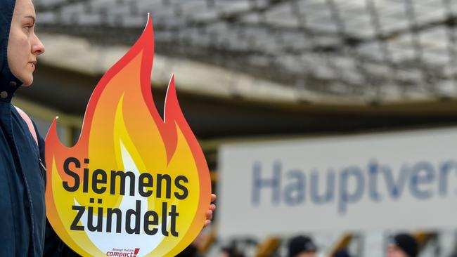 Environmental activists protest with a placard reading "Siemens plays with fire" outside the Siemens AGM in Munich. Picture: AFP