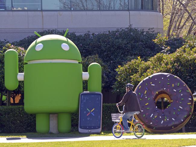 Mountain View, California, USA - February 7, 2011: Man bicycling on Google bike pool bike past Google Android foam robot and Andriod foam phone in front of Building 44 at Googleplex (Google headquarters). Bikes are painted in Google colors and helmets are provided. Bikes speed travel time between distant buildings. Photo: iStock