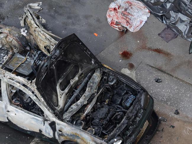 A Russian law enforcement officer inspects stands next to a destroyed car in the courtyard of a residential building following a blast in Balashikha, Moscow region on April 25, 2025. An explosive device ripped through a parked car near Moscow on April 25, 2025 killing General-lieutenant Yaroslav Moskalik, deputy head of the main operational directorate of the military's General Staff, the Investigative Committee said. (Photo by TATYANA MAKEYEVA / AFP)