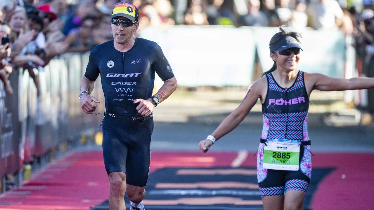 Cairns Iron Man - 3rd Place Pro Winner Sam Appleton about to finish with right local Asako Blain from Bentley Park takes the crowds applause. Picture: Brian Cassey