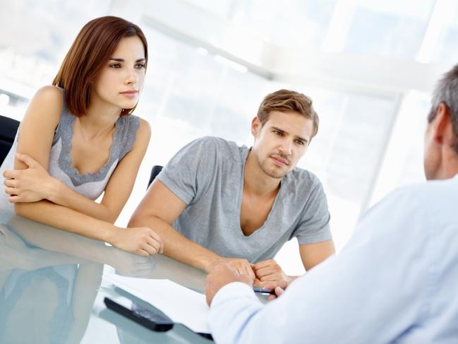 Portrait of beautiful young couple listening to financial adviser in office