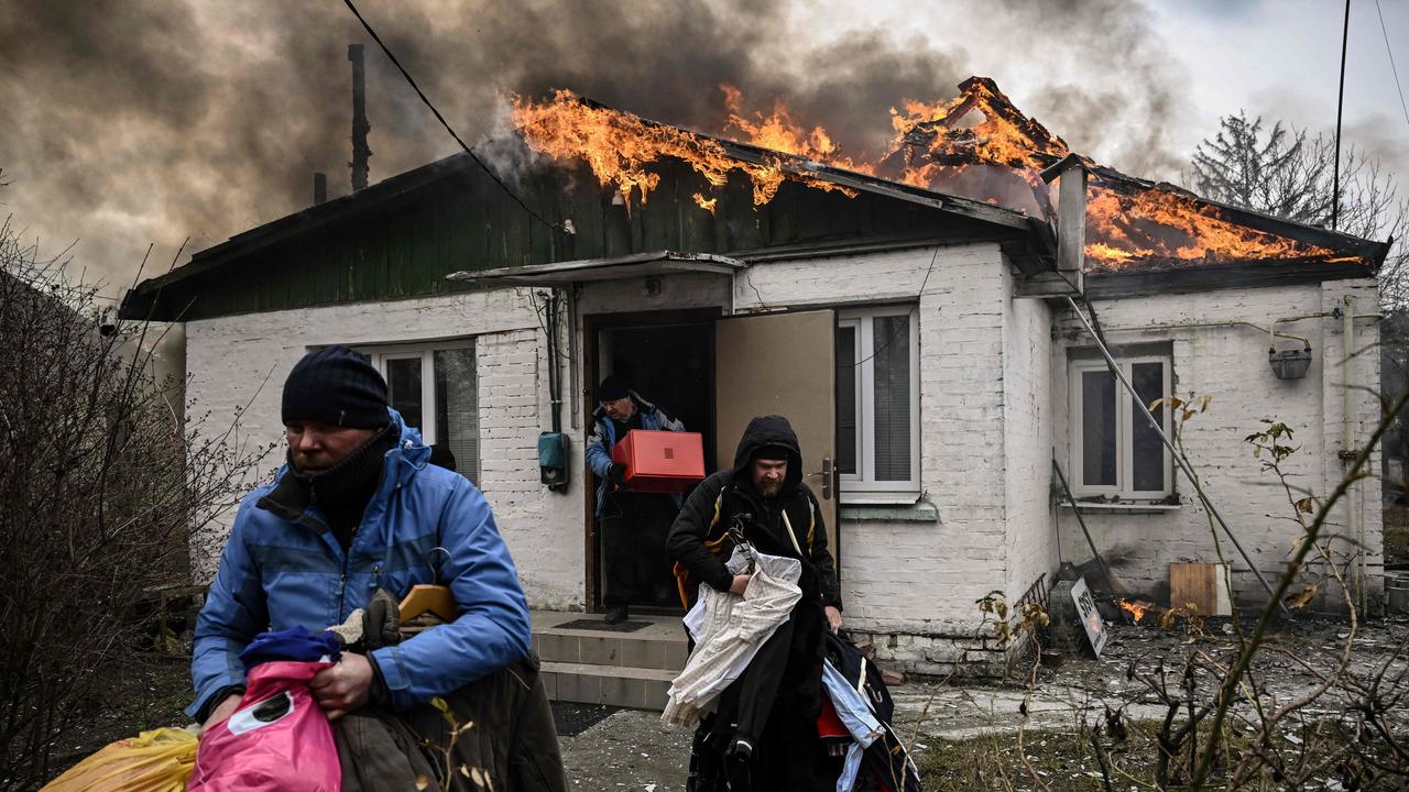 People remove personal belongings from a burning house after being shelled in the city of Irpin, outside Kyiv. Picture: AFP