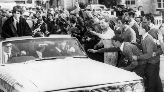 Workers and schoolchildren mob a car carrying British pop sensation The Beatles from Adelaide airport during their Australian tour in 1964. Picture: Keystone/Getty Images