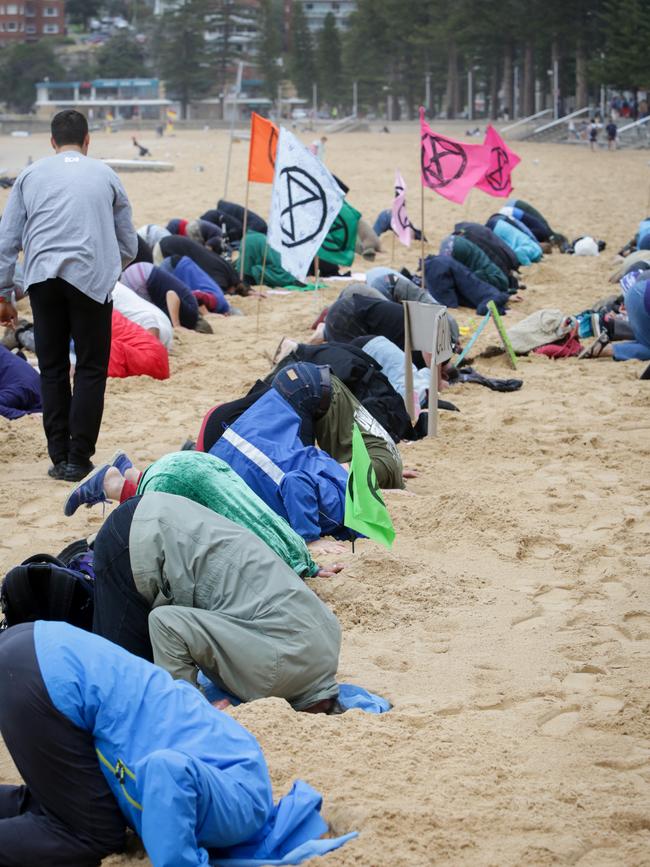 Extinction Rebellion alarmists with their heads in the sand at Manly Beach. Picture: Liam Driver