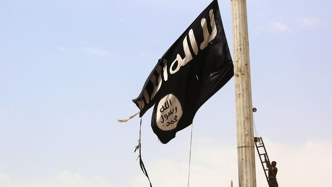 A member of the US-backed Syrian Democratic Forces removes an Islamic State group flag in the town of Tabqa, about 55 kilometres west of Raqa city.