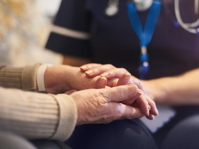 A female nurse consoles a senior patient at home, aged care generic