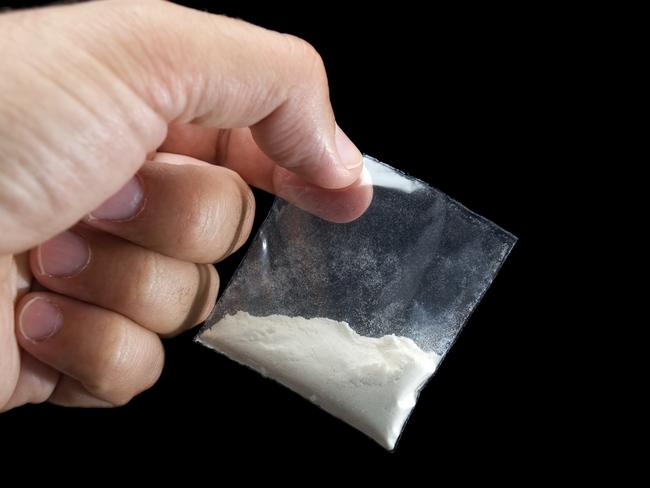 Generic photo of cocaine. Dealer is holding drug bag in his hand on a black background. Picture: iStock