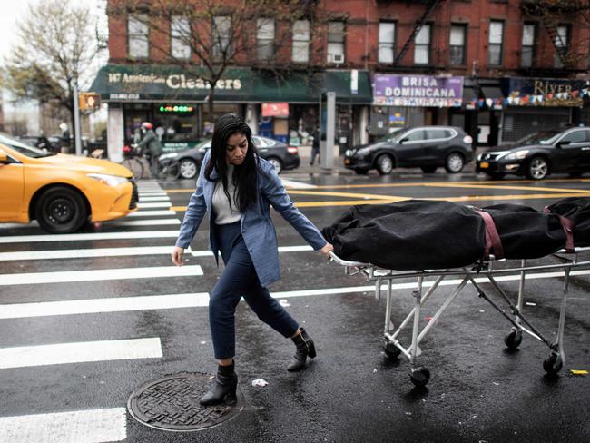 A woman rolls a body on a trolley through the streets of New York. Picture: AFP