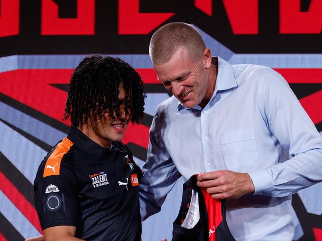 MELBOURNE, AUSTRALIA - NOVEMBER 20:  The number 13 pick, Isaac Kako is presented his Essendon  jumper by Dustin Fletcher during the 2024 Telstra AFL Draft at Marvel Stadium on November 20, 2024 in Melbourne, Australia. (Photo by Michael Willson/AFL Photos via Getty Images)