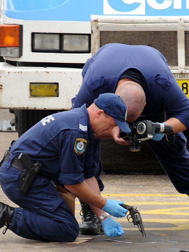 The police officers photograph the gun before taking it for forensic testing.