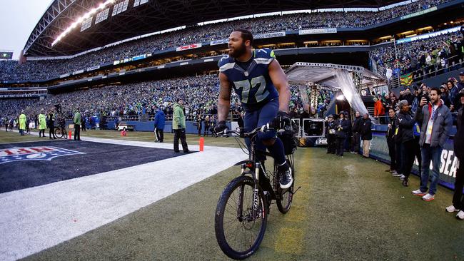 Michael Bennett of the Seattle Seahawks rides a police bike.