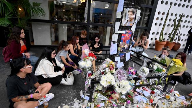 Fans sit in a circle around the floral tributes. Picture: Luis Robayo/AFP