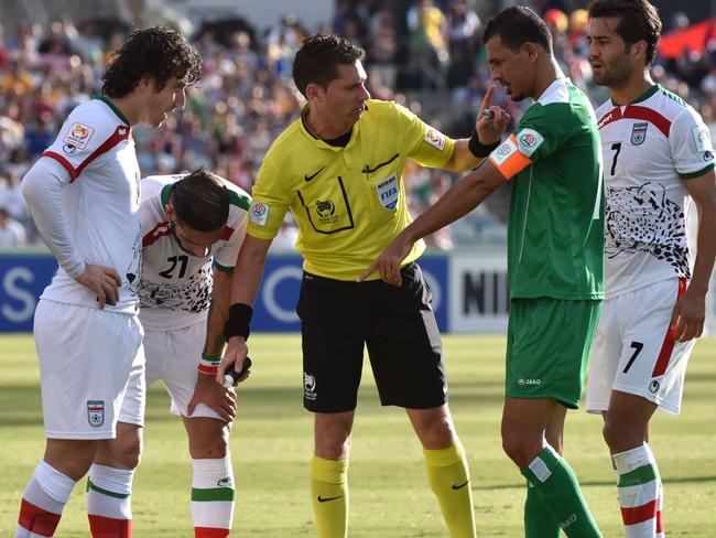 Referee Benjamin Williams (C) speaks to Younus Mahmood (2R) of Iraq during the Asian Cup quarter-final football match between Iraq and Iran in Canberra on January 23, 2015. AFP PHOTO / MARK GRAHAM --- IMAGE RESTRICTED TO EDITORIAL USE - STRICTLY NO COMMERICAL USE --