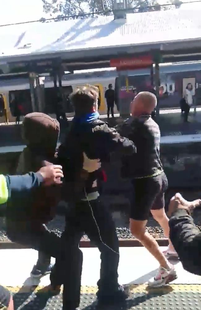 The men come within inches of falling onto the tracks.