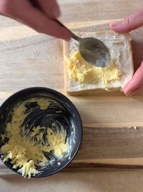 He then mixes butter and Coles parmesan cheese into a bowl and then spreads it onto a slice of bread. Picture: TikTok/airfryerguy