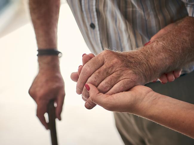 Female nurse supporting senior man to walk. Focus on hands.