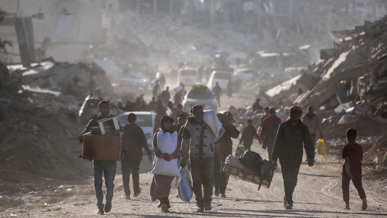 Palestinians carry belongings amid building rubble in a ruined neighbourhood of Gaza's southern city of Rafah on January 20, 2025, as residents return following a ceasefire deal a day earlier between Israel and the Palestinian Hamas group. (Photo by BASHAR TALEB / AFP)