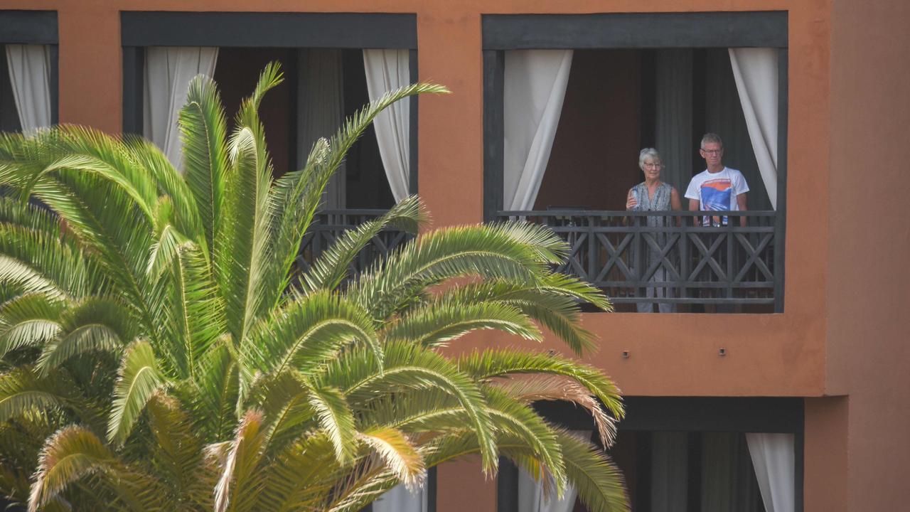 Tourists stand on the balcony of their room at the H10 Costa Adeje Palace Hotel in La Caleta. Picture: Desiree Martin/AFP