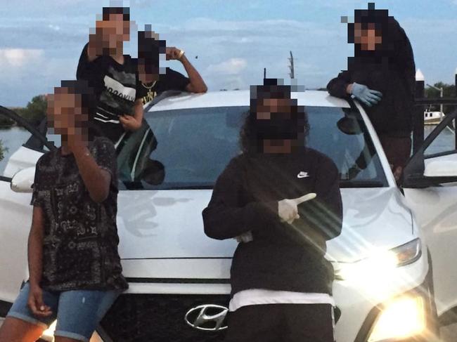 A group of young people pose in front of a stolen car in an image shared to the Townsville crime Instagram page.