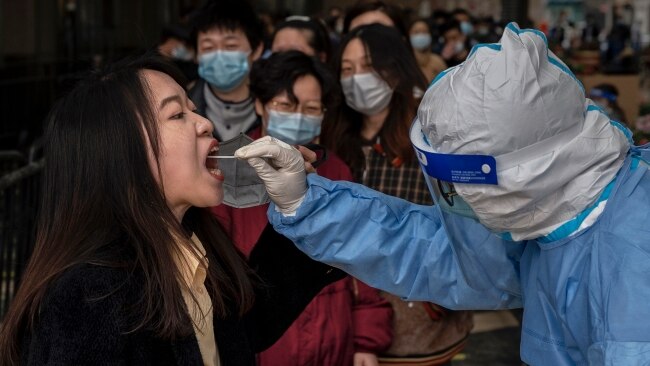 A health worker tests for COVID-19 at a pop-up mass testing site at an office building on March 22 in Beijing, China. Picture: Kevin Frayer/Getty Images