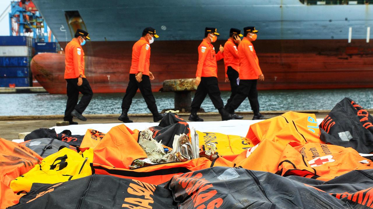 Rescue officials walk past debris collected during the search operation. Picture: Azwar Ipank / AFP