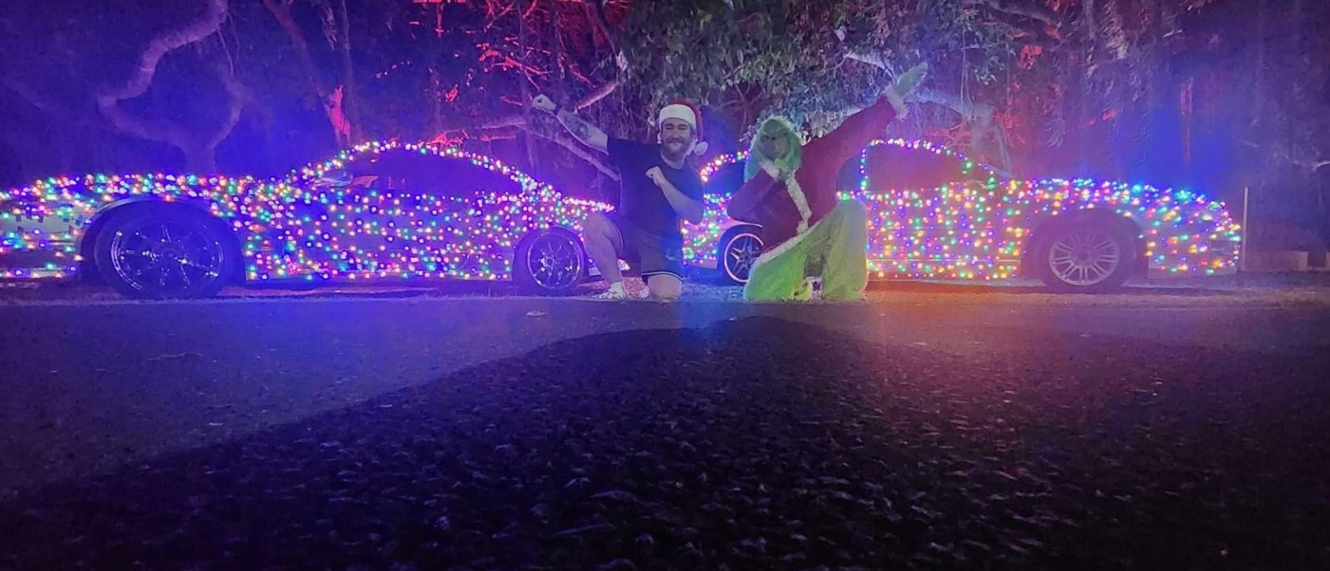 Hayden McIntyre and the Grinch pose in front of their festive vehicles