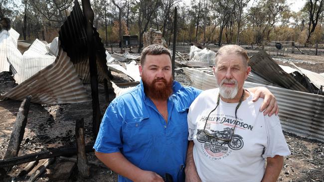 Tom Kelly comforts his dad Mitch Kelly who lost his home in the Tara fires. Picture: Liam Kidston
