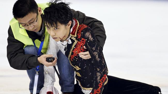 Yuzuru Hanyu of Japan is helped by a medical team member