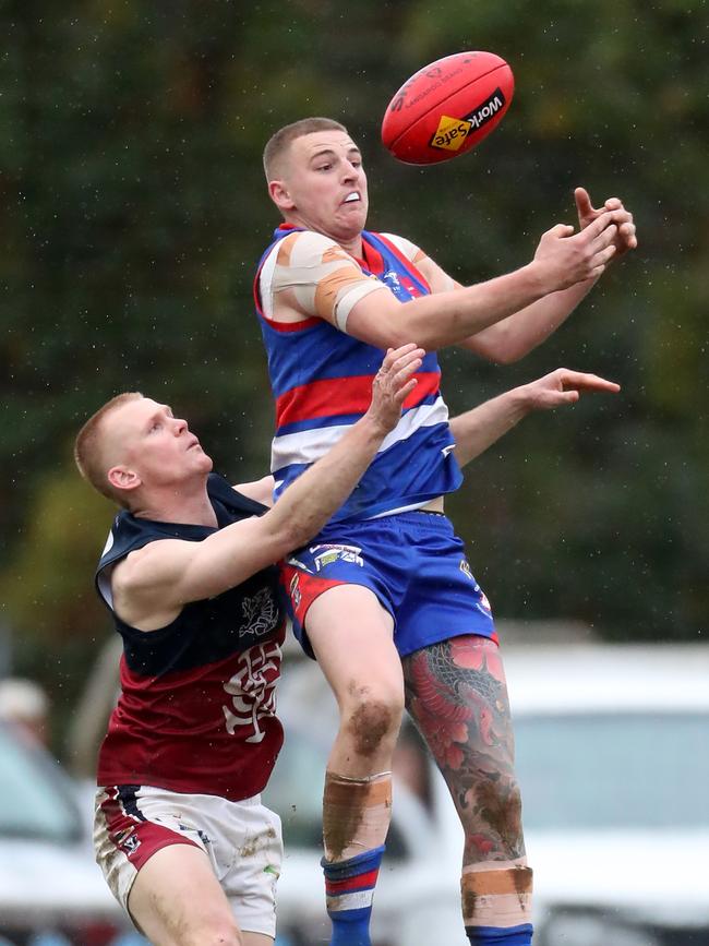 Gisborne’s Jack Scanlon leaps for a mark in front of Sandhurst’s Liam Ireland.