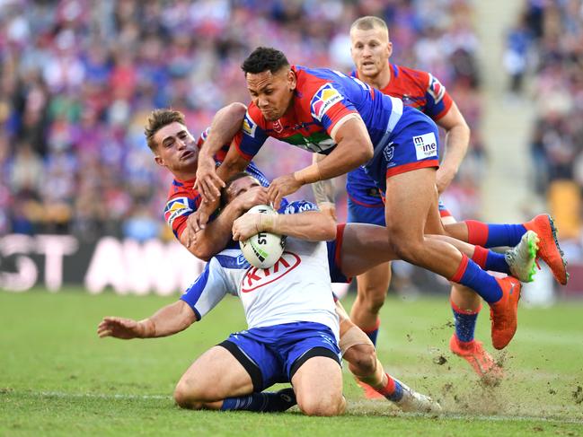 Adam Elliott of the Bulldogs (centre) is tackled by Jesse Ramien (top) of the Knights during the Round 9 NRL match between the Canterbury Bulldogs and the Newcastle Knights. Picture: AAP Image/Dan Peled