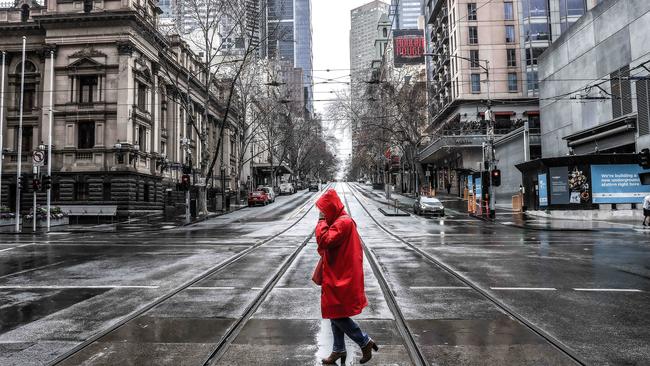 A woman crosses an empty Collins St in Melbourne's CBD. Picture: NCA NewsWire / Ian Currie.