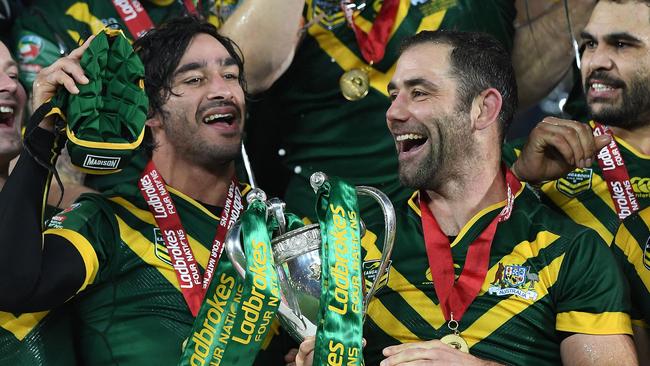 Australia's hooker and captain Cameron Smith holds the trophy as he celebrates with Johnathan Thurston and teammates.