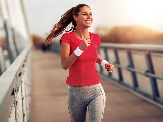 Beautiful fit woman in good shape jogging alone on city bridge.