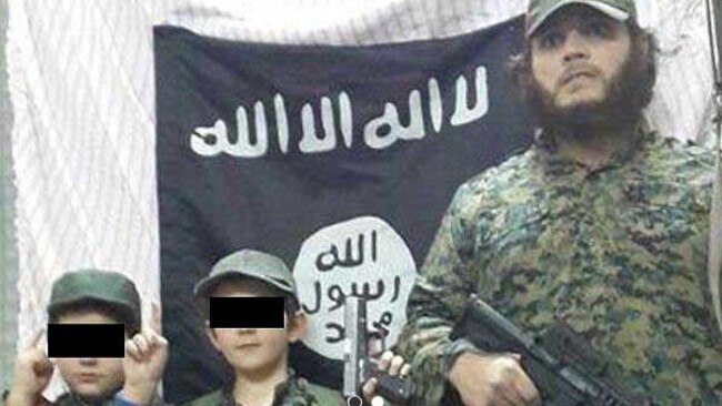 Khaled Sharrouf and boys believed to be two of his three sons stand in front of the Islamic State flag in an image posted on Twitter. Picture: Supplied