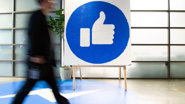 A Facebook employee walks by a sign displaying the ‘like’ sign at Facebook’s corporate headquarters campus in Menlo Park, California. Picture: AFP