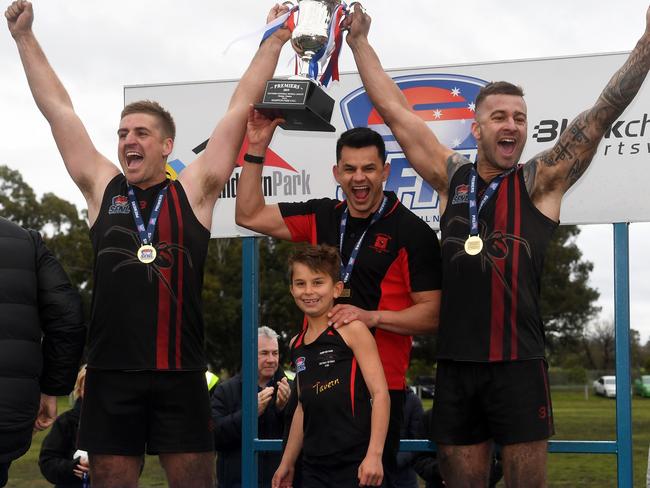 Co-captains Shannon Henwood (left) and Cory Phillips join coach Justin Hill in lifting the premiership cup.