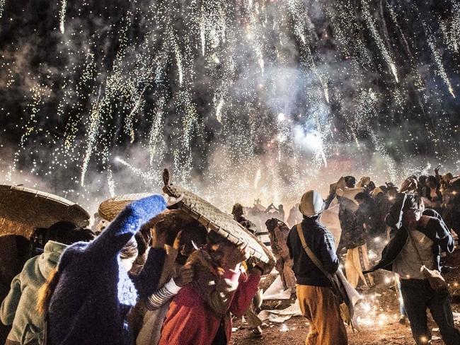 This picture taken on November 12, 2016 shows people protecting themselves from fireworks, being carried by a hot air balloon, that ignited before the balloon was at a sufficient height during the Tazaungdaing Lighting Festival at Taunggyi in Myanmar’s northeastern Shan State. Picture: AFP PHOTO / YE AUNG THU