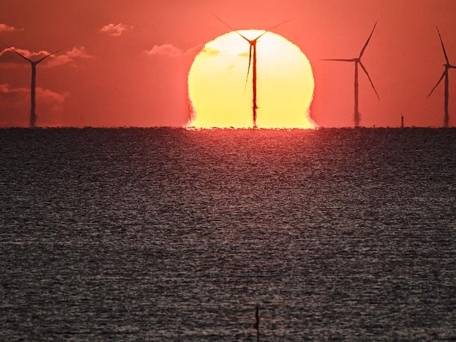 (FILES) A photograph taken on December 9, 2022 shows the sun setting over an offshore wind farm, off the coast of the French Western city of Saint-Nazaire. Recyclable blades, carbon-free concrete... wind turbine designers are multiplying innovations to green their machines, an environmental issue but also a political object for critics of this energy. (Photo by LOIC VENANCE / AFP)