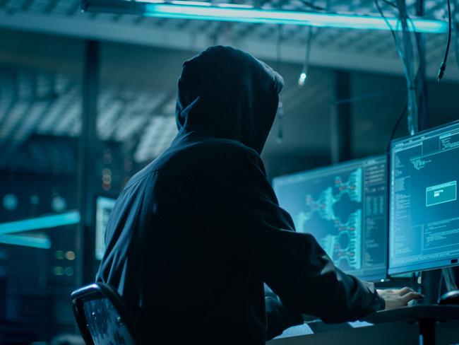 Shot from the Back to Hooded Hacker Breaking into Corporate Data Servers from His Underground Hideout. Place Has Dark Atmosphere, Multiple Displays, Cables Everywhere; scams, scammer generic