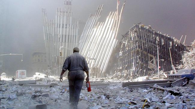 A man with a fire extinguisher walks through rubble after the collapse of the first World Trade Center Tower in New York. Picture: AFP.