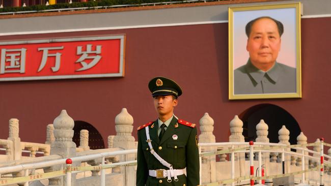 A People’s Armed Police officer stands before a portrait of Mao Zedong in Beijing.