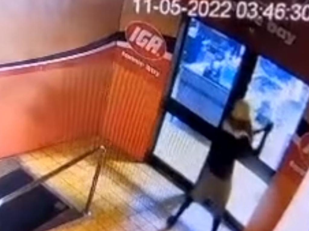 IGA Fannie Bay CCTV footage still of an unidentified offender hacking into the front door glass. Picture: Supplied.