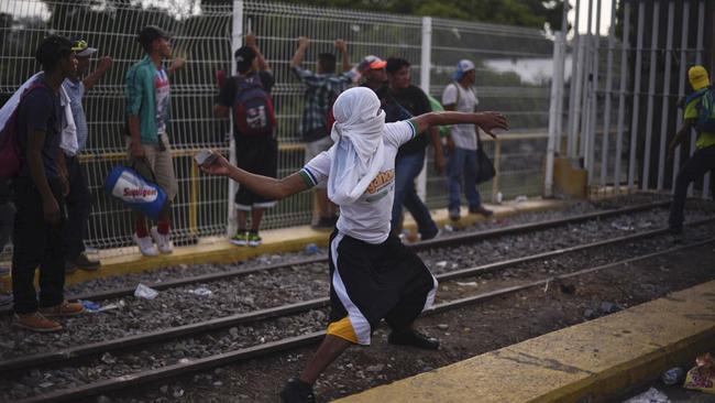 A Honduran migrant throws stones at the border between Guatemala and Mexico. Picture: Billy Santiago/AP