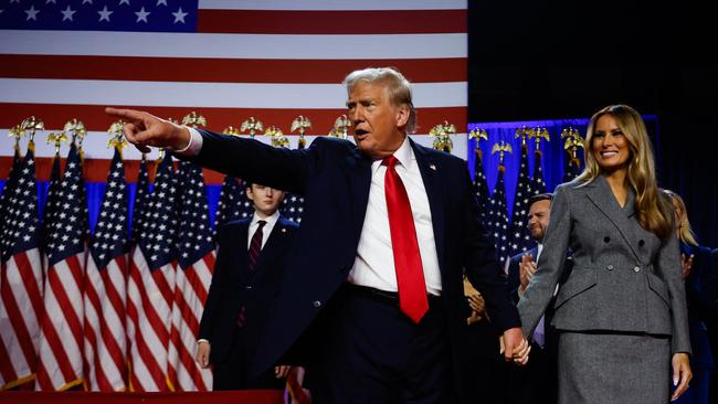 Donald Trump points to supporters with Melania Trump during an election night event at the Palm Beach Convention Centre.