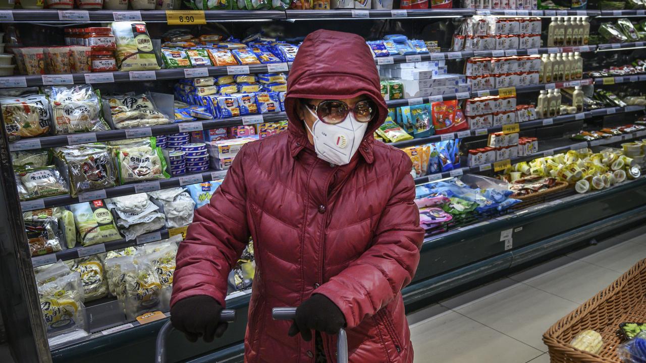 A Chinese woman wears a protective mask and sunglasses as she shops for groceries at a supermarket in Beijing. Picture: Getty Images/Kevin Frayer