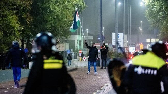 A man waving a Palestinian flag in front of police officers during a demonstration in Amsterdam on the night of the soccer match between Ajax and Maccabi Tel Aviv. Picture: Jeroen Jumelet/AFP/Getty Images