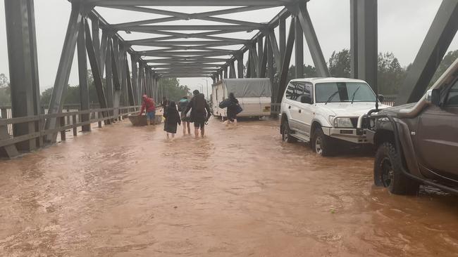 People trudge through flood water at the Ballina Street Bridge to meet a boat at the other end in South Lismore on February 28, 2022.