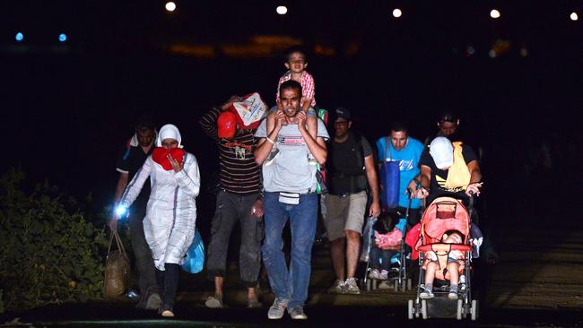 Migrants walk after crossing from Macedonia towards Serbia, near the village of Miratovac to the overcrowded transit camp in Presevo late on September 4, 2015. AFP PHOTO / LOUISA GOULIAMAKI