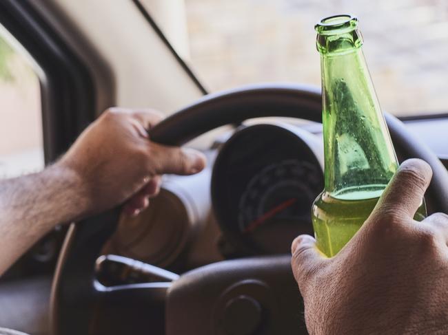 An unrecognizable man drinking beer while driving car. Concepts of driving under the influence, drunk driving or impaired driving. Drink driving generic. Picture: iSTOCK