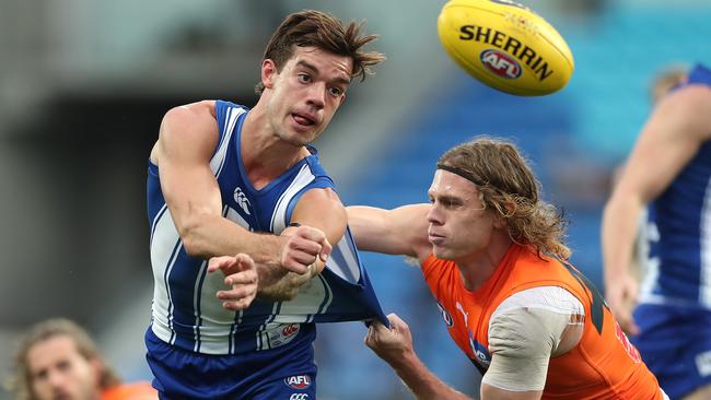 HOBART, AUSTRALIA - JUNE 13: Jy Simpkin of the Kangaroos handballs whilst being tackled by Adam Kennedy of the Giants during the round 13 AFL match between the North Melbourne Kangaroos and the Greater Western Sydney Giants at Blundstone Arena on June 13, 2021 in Hobart, Australia. (Photo by Mark Metcalfe/AFL Photos/via Getty Images)